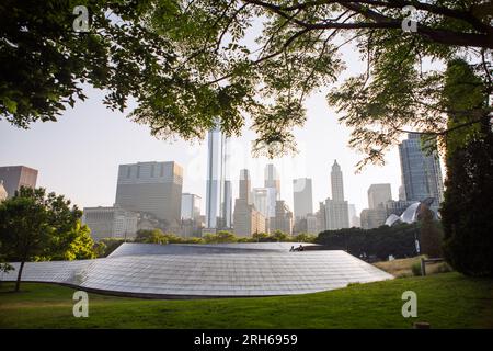 Vue latérale du pont piéton BP revêtu de panneaux en acier inoxydable brossé, Chicago, Illinois, USA, au coucher du soleil tombant derrière les bâtiments Banque D'Images