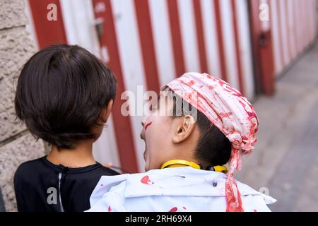 Enfant effrayant son ami dans la rue avec des costumes d'halloween Banque D'Images