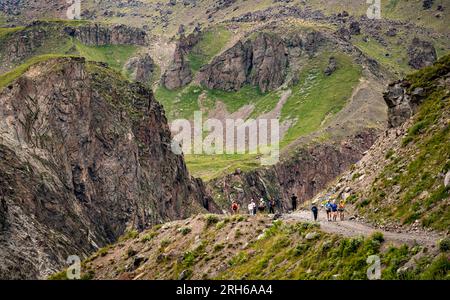 Alpes, Italie - 13 août 2023 : trekking en montagne. touristes trekking haut dans les montagnes. Randonneurs avec des bâtons de trekking sur la pente sur fond de hi Banque D'Images