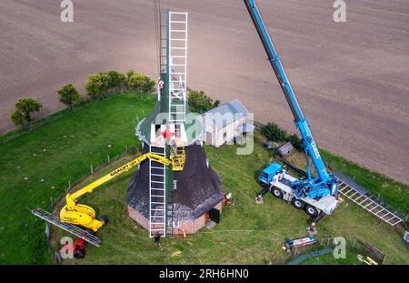 14 août 2023, Mecklembourg-Poméranie occidentale, Rövershagen : assemblage de la deuxième aile de la nouvelle croix d'aile du moulin à vent de Mecklembourg de Rövershagen. (Photo aérienne prise avec un drone) les quatre nouvelles ailes mesurent 10,5 mètres de long et 2,3 mètres de large. Les ailes du moulin, construit en 1881, étaient inopérantes depuis 2018 en raison de l'intrusion d'humidité et de la pourriture fongique. De plus, l'extrémité d'une aile s'était brisée lors d'une tempête en 2021. Les coûts de la restauration jusqu'à présent s'élèvent à environ 30 000 euros et sont pris en charge par la Fondation allemande pour la protection des monuments. Photo : Jens Büttner/dpa Banque D'Images