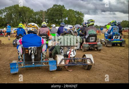 Les pilotes s'assoient sur leurs tondeuses de course en attendant de se voir attribuer des positions de départ dans le cadre du British Lawn Mower Racing Associ, une course annuelle de tondeuses à gazon de style le Mans Banque D'Images