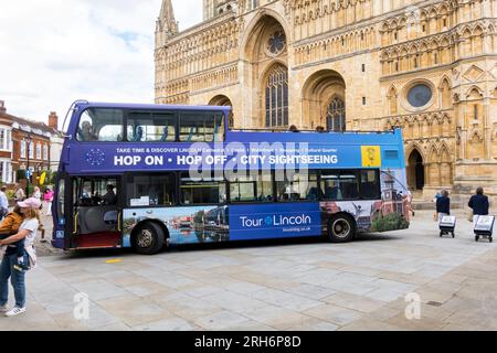 HOP ON - HOP OFF - bus touristique de la ville attendant les clients en face de la cathédrale de Lincoln, Minster Yard, Lincoln City, Lincolnshire, Angleterre, ROYAUME-UNI Banque D'Images