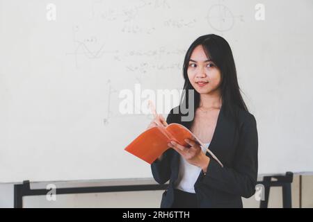 professeur asiatique tenant le livre sur fond de tableau blanc Banque D'Images