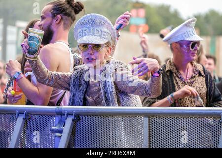 Couple portant une casquette à bijoux bride and Groom dans une foule de gens au Boomtown Fair Festival. Boomtown aka Boomtown Fair est un festival de musique britannique qui se tient chaque année dans le parc national de South Downs, près de Winchester, Hampshire. Depuis 2009, Boomtown a offert un line-up diversifié de groupes, DJs et conférenciers se produisent sur de nombreuses scènes différentes chaque événement annuel est connu sous le nom de Chapitre et se développe sur la ligne de l'histoire de l'année précédente, racontée à travers les décors et les acteurs en direct qui errent sur le site. (Photo de Dawn Fletcher-Park/SOPA Images/Sipa USA) Banque D'Images