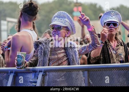 Couple portant une casquette à bijoux bride and Groom dans une foule de gens au Boomtown Fair Festival. Boomtown aka Boomtown Fair est un festival de musique britannique qui se tient chaque année dans le parc national de South Downs, près de Winchester, Hampshire. Depuis 2009, Boomtown a offert un line-up diversifié de groupes, DJs et conférenciers se produisent sur de nombreuses scènes différentes chaque événement annuel est connu sous le nom de Chapitre et se développe sur la ligne de l'histoire de l'année précédente, racontée à travers les décors et les acteurs en direct qui errent sur le site. (Photo de Dawn Fletcher-Park/SOPA Images/Sipa USA) Banque D'Images