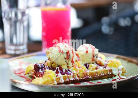 Farine complète gaufre belge croustillante avec une boule de crème glacée et garnitures. Gaufre belge avec glace à la vanille, sauce fraise, crème anglaise et ca Banque D'Images