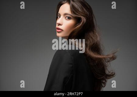 Modèle asiatique tendance avec maquillage et coiffure posant en veste noire isolé sur gris Banque D'Images