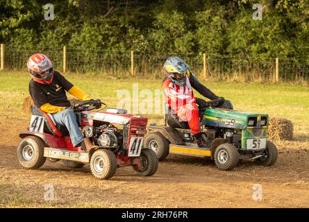 Les pilotes de tondeuses à gazon de course se battent pour garder le contrôle sur un virage dans la BLMRA 500, une course de tondeuses à gazon de nuit de 500 miles dans le style du Mans dans un champ de l'Ouest Banque D'Images