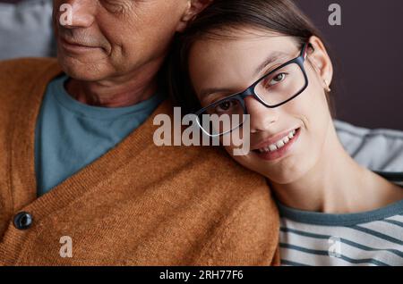 Gros plan d'une adolescente atteinte de paralysie cérébrale penchée sur l'épaule du père et souriant à la caméra Banque D'Images