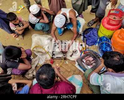 Un homme réparant des cuisinières. Environ 919 000 000 réfugiés Rohingyas vivent dans les camps de Kutupalong et de Nayapara dans la région de Cox’s Bazar, qui sont devenus l’un des camps les plus vastes et les plus densément peuplés au monde. Bangladesh. Banque D'Images