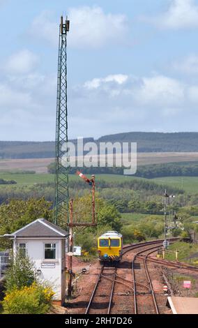 Machine de bourrage de voie ferrée passant la boîte de signal mécanique et le signal sémaphore de support haut à New Cumnock, Ayrshire, Écosse, Royaume-Uni Banque D'Images