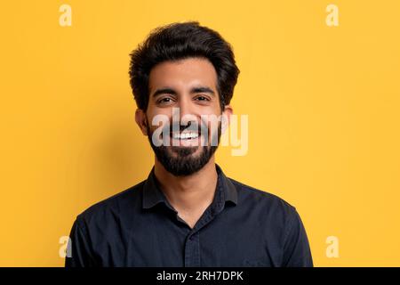 Portrait de bel homme indien souriant posant sur fond de studio jaune Banque D'Images