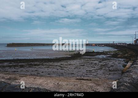 Le front de mer à Donaghadee, County Down, Irlande du Nord avec le phare blanc bien connu au loin. Banque D'Images