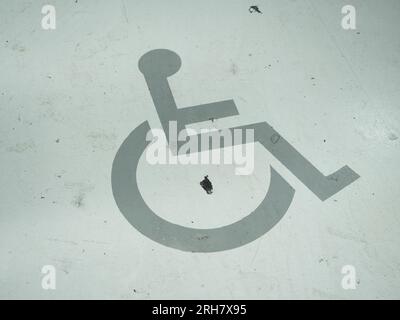 Un symbole de fauteuil roulant est peint dans la rue. Il marque un parking pour personnes handicapées. Banque D'Images