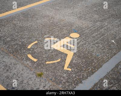 Un symbole de fauteuil roulant est peint dans la rue. Il marque un parking pour personnes handicapées. Banque D'Images