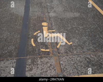 Un symbole de fauteuil roulant est peint dans la rue. Il marque un parking pour personnes handicapées. Banque D'Images