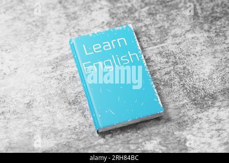 Manuel d'anglais sur une table de ciment. Apprentissage de l'anglais. Grammaire anglaise. Apprendre le livre anglais pour l'apprentissage des langues. Rendu 3D. Banque D'Images