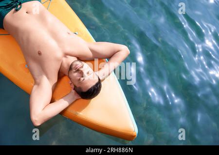 Homme allongé sur la planche de SUP dans la mer, vue de dessus. Espace pour le texte Banque D'Images