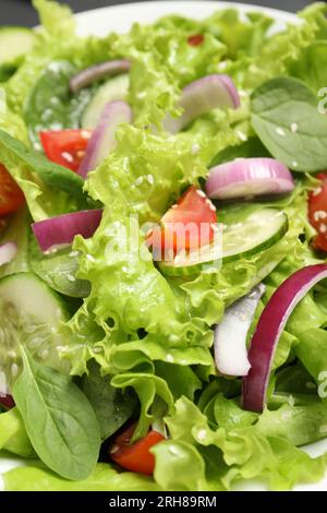 Délicieuse salade avec des concombres et des tomates dans un bol blanc, gros plan Banque D'Images