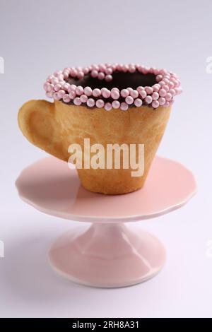 Délicieuse tasse à biscuit comestible décorée avec des saupoudrages sur fond blanc Banque D'Images