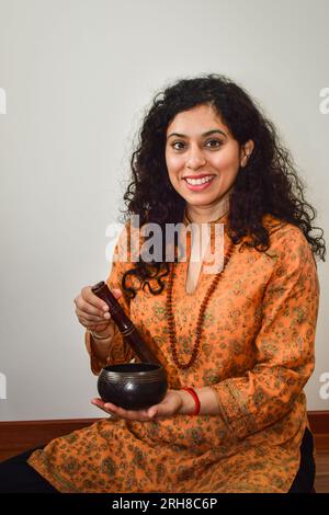 Une femme pratiquant la méditation et la guérison avec un bol chantant tibétain. Banque D'Images