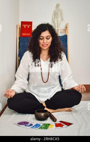 Une femme pratiquant la méditation et la guérison avec un bol chantant tibétain. Banque D'Images