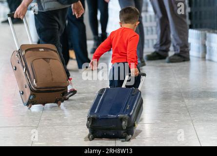 Photo de dossier datée du 26/08/2023 d'un jeune garçon tirant une valise alors que des réfugiés arrivent d'Afghanistan à l'aéroport d'Heathrow, Londres. De nombreuses familles afghanes ont été déçues par l’accueil chaleureux promis au Royaume-Uni, a déclaré un groupe de réflexion qui a appelé à tirer des leçons afin que les futurs groupes de réfugiés puissent être mieux soutenus. More in Common, une organisation fondée à la suite du meurtre du député travailliste JO Cox, a reconnu le succès des efforts visant à installer des milliers de personnes dans des logements permanents après avoir fui la prise de pouvoir par les talibans il y a deux ans. Date d'émission : mardi 15 août 2023. Banque D'Images