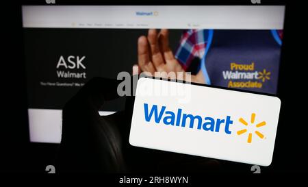Personne détenant un téléphone intelligent avec le logo de la société de vente au détail américaine Walmart Inc. Sur l'écran devant le site Web. Concentrez-vous sur l'affichage du téléphone. Banque D'Images
