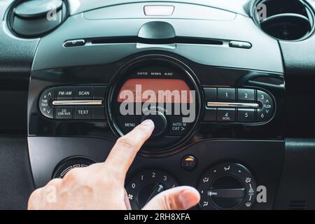 Fermez la main de l'homme qui règle l'autoradio. Concept de système audio pour voiture. Banque D'Images