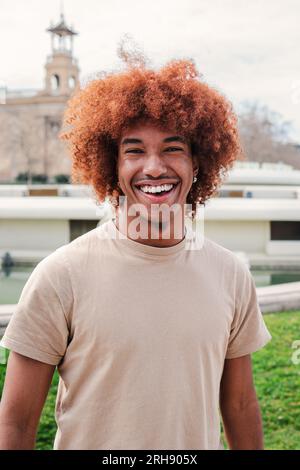Portrait individuel d'un homme afro-américain joyeux avec des cheveux afro regardant la caméra avec une expression amicale. Jeune lycéen souriant. Adolescent mâle riant debout dehors. Photo de haute qualité Banque D'Images