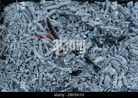Fond de texture de charbons gris. Gros plan sur les braises de texture. Combustion, décomposition du charbon de bois, charbons, cendres fumantes avec le feu dans le barbecue en acier brazier.BBQ barbecue saison en plein air. Photo de haute qualité Banque D'Images