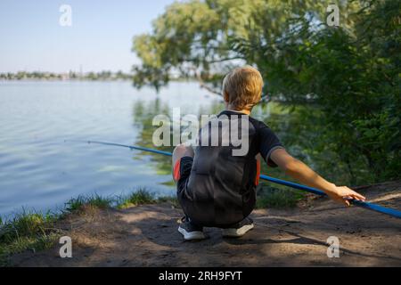 Le garçon se prépara à hameçonner le poisson. Pêche sportive sur la rivière en été. Banque D'Images