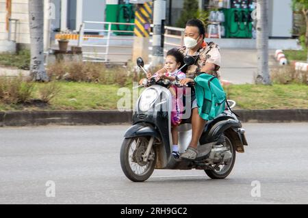 RATCHABURI, THAÏLANDE, octobre 18 2022, Un homme conduit une moto avec une petite fille debout sur le sol. Banque D'Images