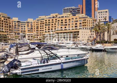 St Julians, Malte - 2 août 2023 : bateaux à moteur de luxe amarrés devant les immeubles d'appartements entourant la marina dans le développement de Portomaso Banque D'Images