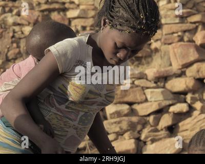 maman africaine portant son enfant sur le dos. Montrer la belle maternité des Africains. les mères portant leurs enfants. Banque D'Images