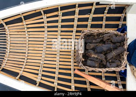 Gros plan du bateau traditionnel à cassis à la main avec creal ou panier en osier de gazon ou de combustible tourbe pour le chauffage. Comté de Donegal, Irlande Banque D'Images