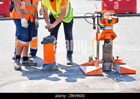 Les travailleurs routiers utilisent une carotteuse pour extraire les carottes d'un revêtement asphalté pendant les réparations de la route. Espace de copie. Banque D'Images