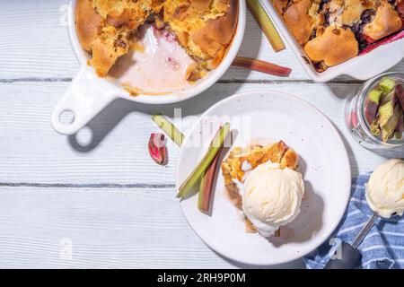 Tarte parée à la framboise aux baies, gâteau maison à l'éponge avec rhubarbe sucrée et fraise, servi avec boule de glace à la vanille, sur un k en bois blanc ensoleillé Banque D'Images