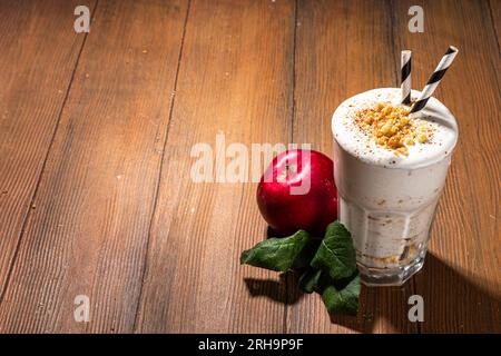 Milk-shake aux pommes chargé maison, smoothie aux protéines de pomme d'automne rouge avec crumble à la tarte et épices, boisson de petit-déjeuner de saison d'automne saine, sur W confortable Banque D'Images