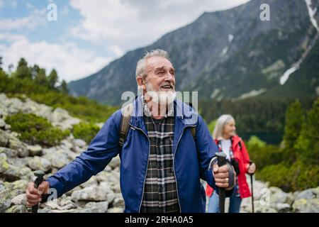 Potrait d'un homme âgé actif randonnant avec sa femme dans les montagnes d'automne. Banque D'Images