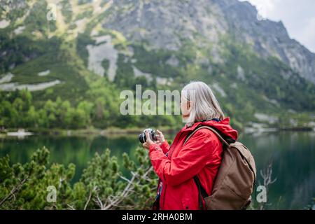Potrait de femme âgée active randonnant dans les montagnes d'automne. Banque D'Images