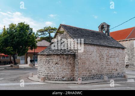 Pins poussant sur le toit de la chapelle de la place Nerezisca, île de Brac, Croatie. Banque D'Images