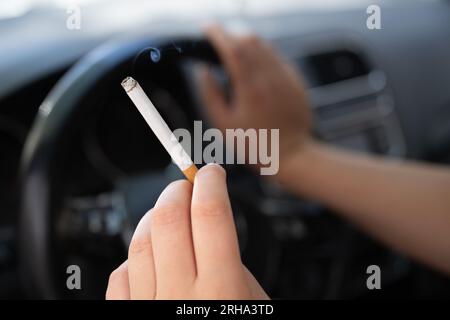 Dresde, Allemagne. 15 août 2023. Une femme est assise dans une voiture et tient une cigarette. Selon le ministère fédéral de la Santé, il ne sera plus permis de fumer dans les voitures lorsque des enfants ou des femmes enceintes seront passagers. Crédit : Sebastian Kahnert/dpa/Alamy Live News Banque D'Images