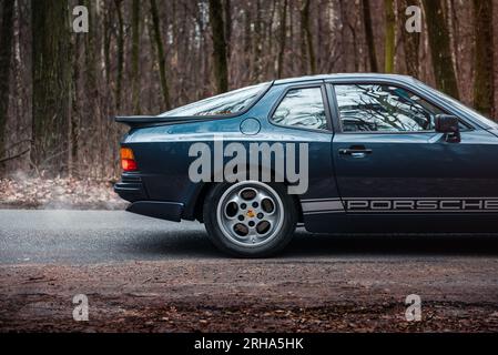 Porsche 944 bleu foncé dans la forêt d'automne. Vue de profil latérale de custode arrière d'une voiture de sport des années 1980. Banque D'Images