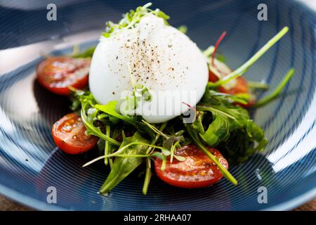 Burrata avec confiture de paprika-truffe et salade de tomates cerises-grappes. Délicieux gros plan de cuisine traditionnelle italienne saine servi pour le déjeuner dans le moderne Banque D'Images