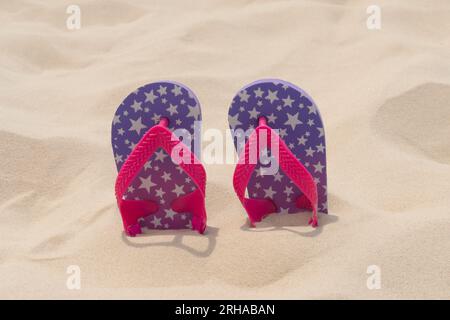 Pantoufles reposent dans le sable sur la plage. Vacances d'été, voyage et concept de tourisme. Repos estival. Fêtes de fin d'année Banque D'Images