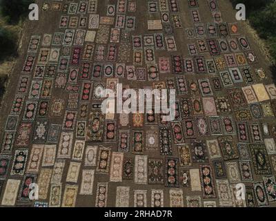 (230815) -- ANTALYA, 15 août 2023 (Xinhua) -- cette photo aérienne prise le 15 août 2023 montre que des tapis turcs tissés à la main sont posés sur de vastes champs pour être exposés à la lumière du soleil dans le district de Dosemealti, province d'Antalya, T¨¹rkiye. Cette technique de bronzage des tapis turcs est une méthode qui a été utilisée dans les temps anciens pour adoucir leurs couleurs et éliminer les germes qu'ils pourraient contenir. Le quartier lui-même est un centre de petits tapis tissés à la main colorés avec des colorants naturels dérivés de plantes. Les vastes champs des agriculteurs se transforment en un lieu pour les tapis qui passent à l'étape finale avant leur vente, après la récolte estivale Banque D'Images