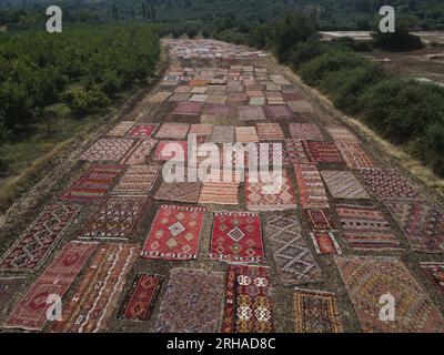 (230815) -- ANTALYA, 15 août 2023 (Xinhua) -- cette photo aérienne prise le 15 août 2023 montre que des tapis turcs tissés à la main sont posés sur de vastes champs pour être exposés à la lumière du soleil dans le district de Dosemealti, province d'Antalya, T¨¹rkiye. Cette technique de bronzage des tapis turcs est une méthode qui a été utilisée dans les temps anciens pour adoucir leurs couleurs et éliminer les germes qu'ils pourraient contenir. Le quartier lui-même est un centre de petits tapis tissés à la main colorés avec des colorants naturels dérivés de plantes. Les vastes champs des agriculteurs se transforment en un lieu pour les tapis qui passent à l'étape finale avant leur vente, après la récolte estivale Banque D'Images