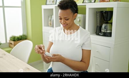 Jeune femme enceinte mesurant du sucre assis sur une table dans la salle à manger Banque D'Images