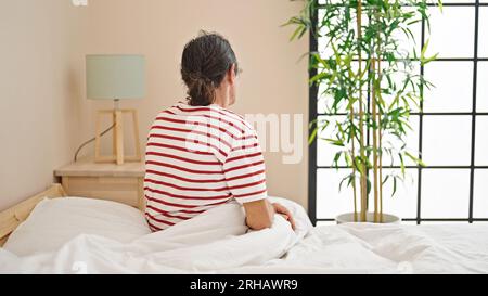 Homme d'âge moyen assis sur le lit à l'arrière dans la chambre Banque D'Images